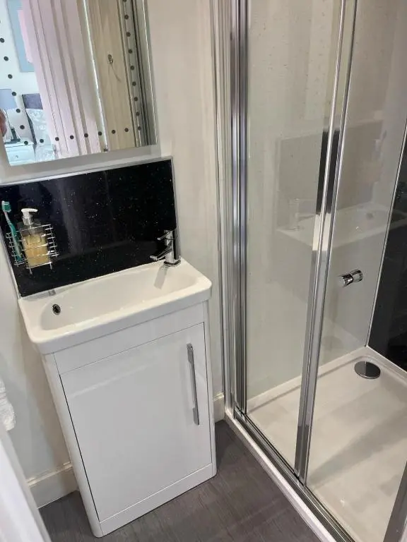 a white bathroom with a shower and a white sink at THE KEMPS 7bed 6 bathroom PARKING for 3 vehicles Ideal for contractors Next to LIDLE part of Langleycottageandapartments portfolio REDUCTION FOR LONG STAYS in Inverness