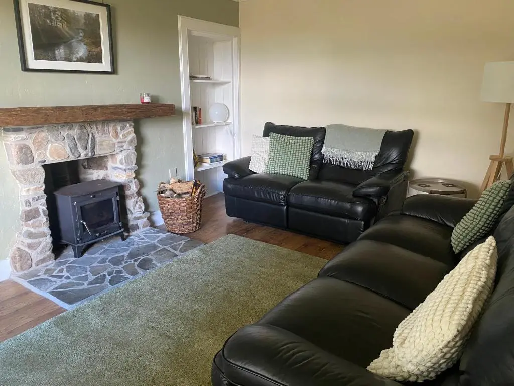 a living room with a couch and a fireplace at Struan Cottage in Knockandhu