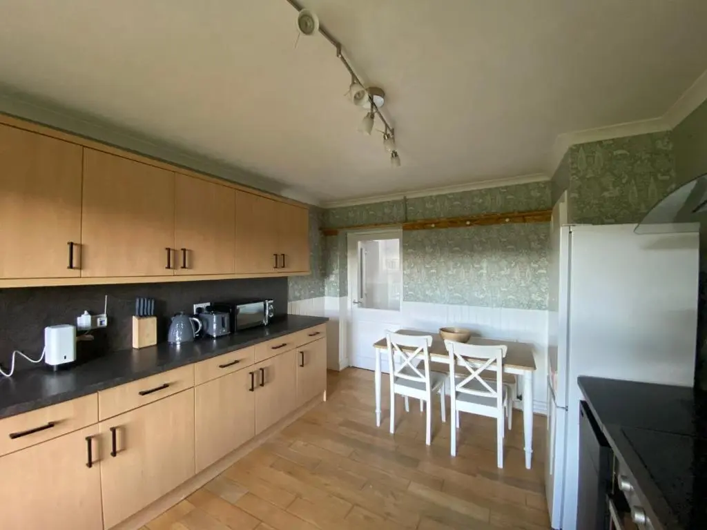 a kitchen with wooden cabinets and a table and chairs at Struan Cottage in Knockandhu