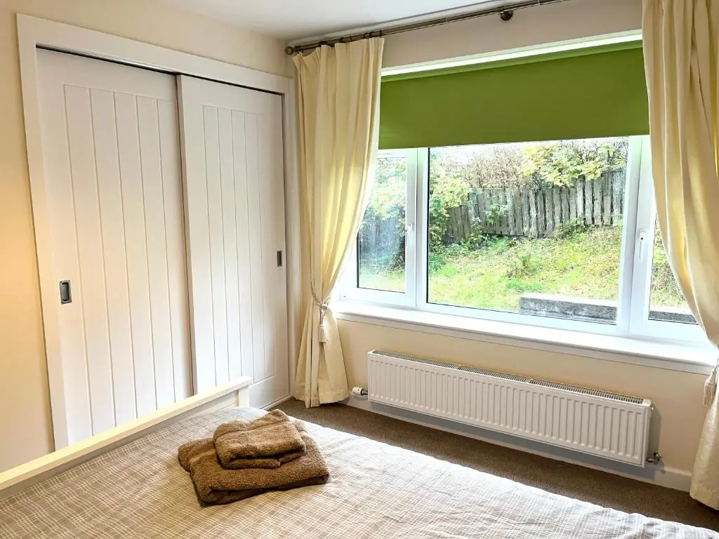 a bedroom with a bed and a large window at House By The Sea in Portsoy