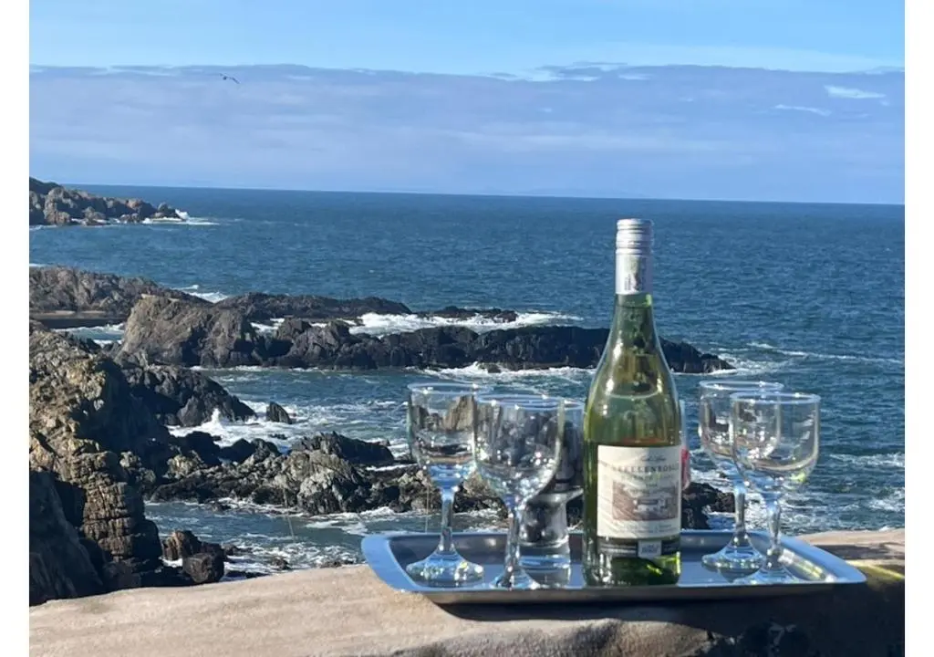 a bottle of wine sitting on a tray with wine glasses at House By The Sea in Portsoy