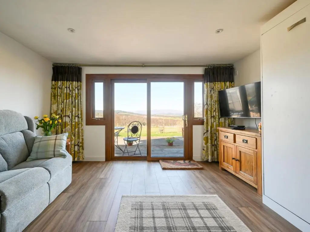 a living room with a couch and a television at Studio Crofters View by Interhome in Inverness