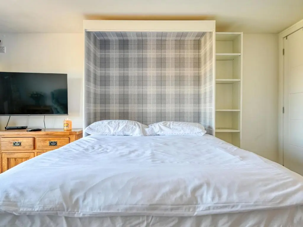 a bedroom with a white bed and a television at Studio Crofters View by Interhome in Inverness