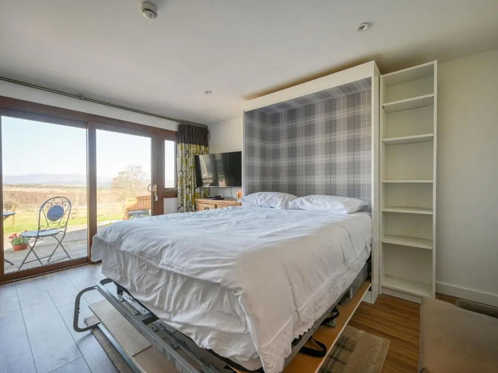 a bedroom with a large bed and a large window at Studio Crofters View by Interhome in Inverness