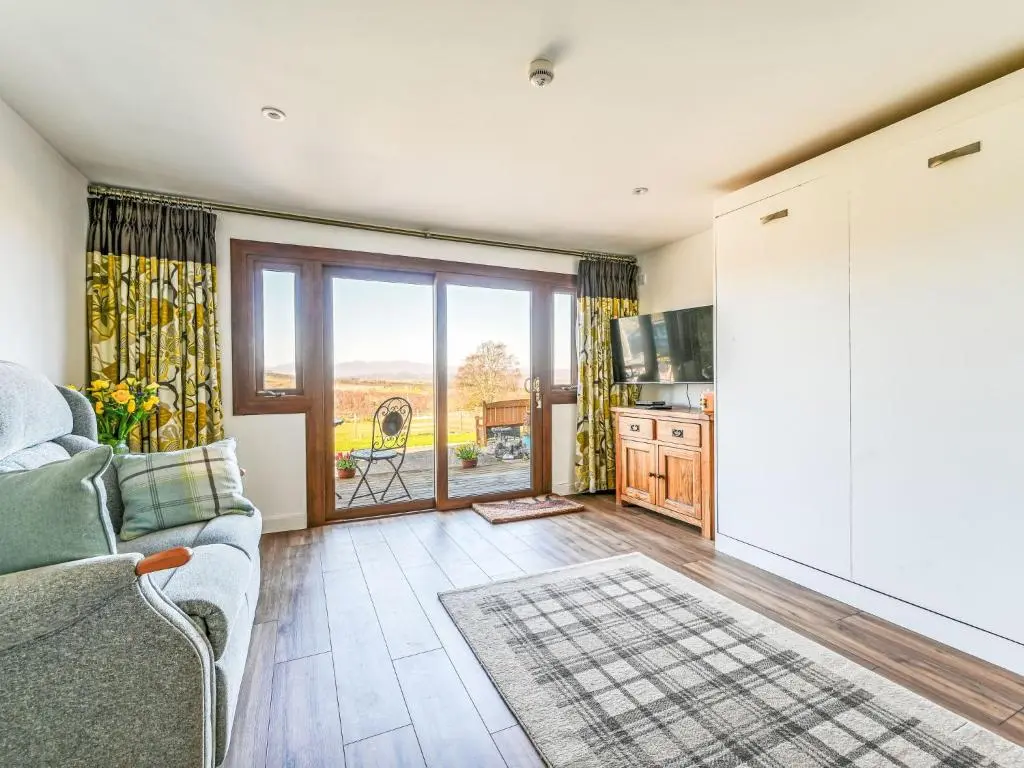a living room with a couch and a large window at Studio Crofters View by Interhome in Inverness