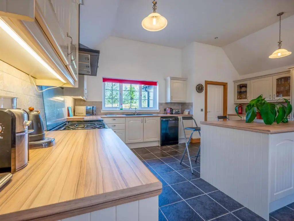 a large kitchen with white cabinets and a wooden counter top at Holiday Home Mountain View Lodge by Interhome in Whitebridge