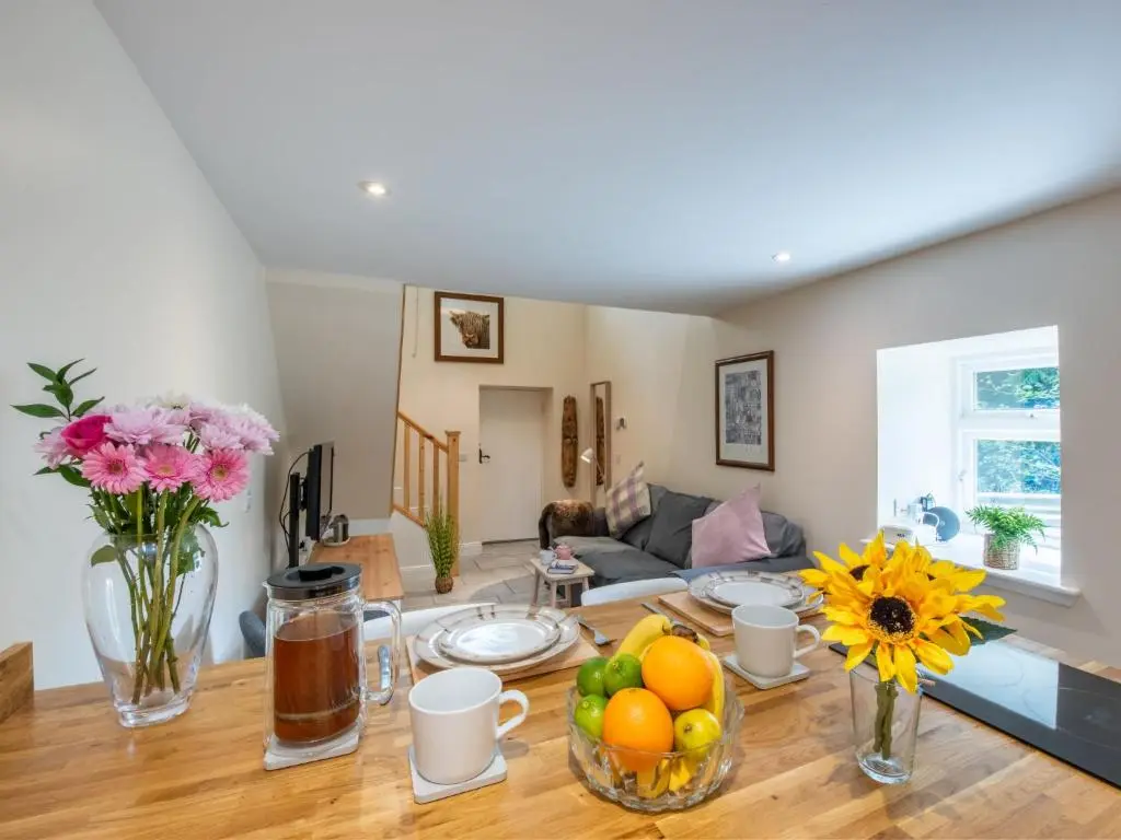 a living room with a table with fruits and flowers at Holiday Home Betty's Bothy by Interhome in Drumnadrochit