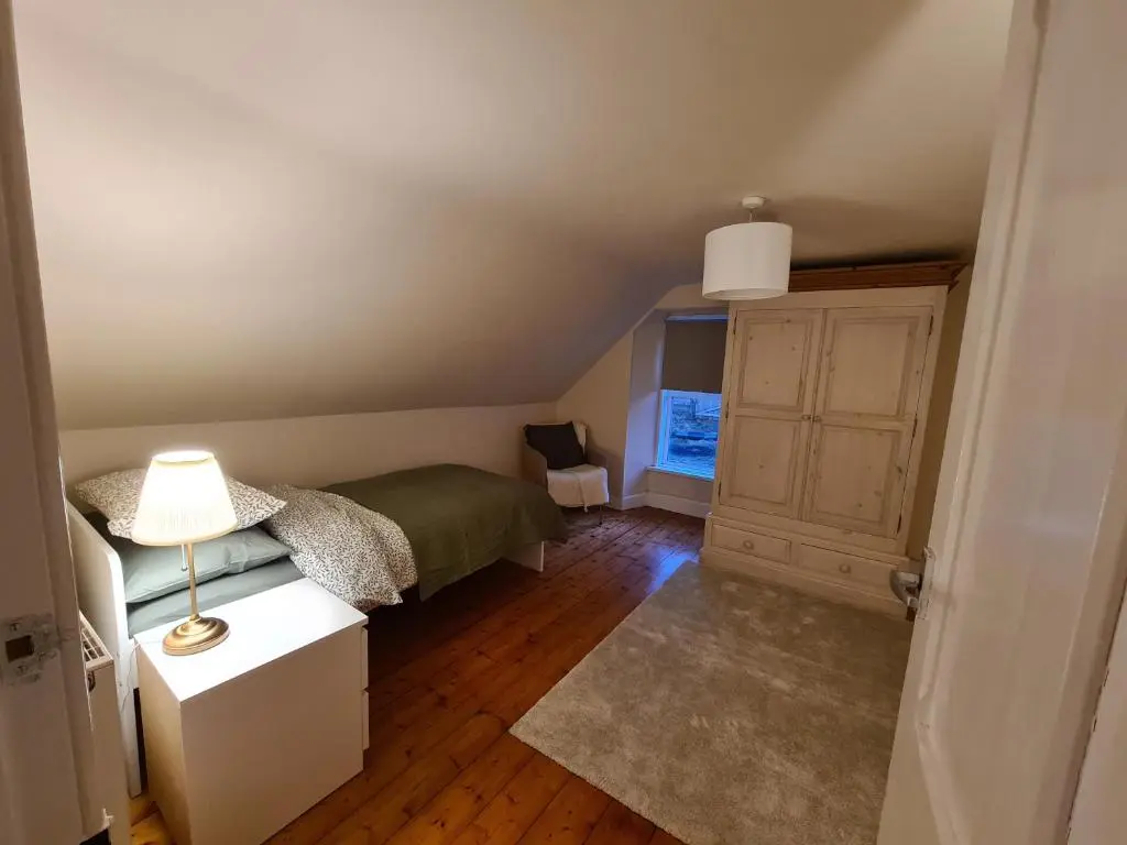 a bedroom with a bed and a lamp on a table at Alltachbeg in Tomintoul
