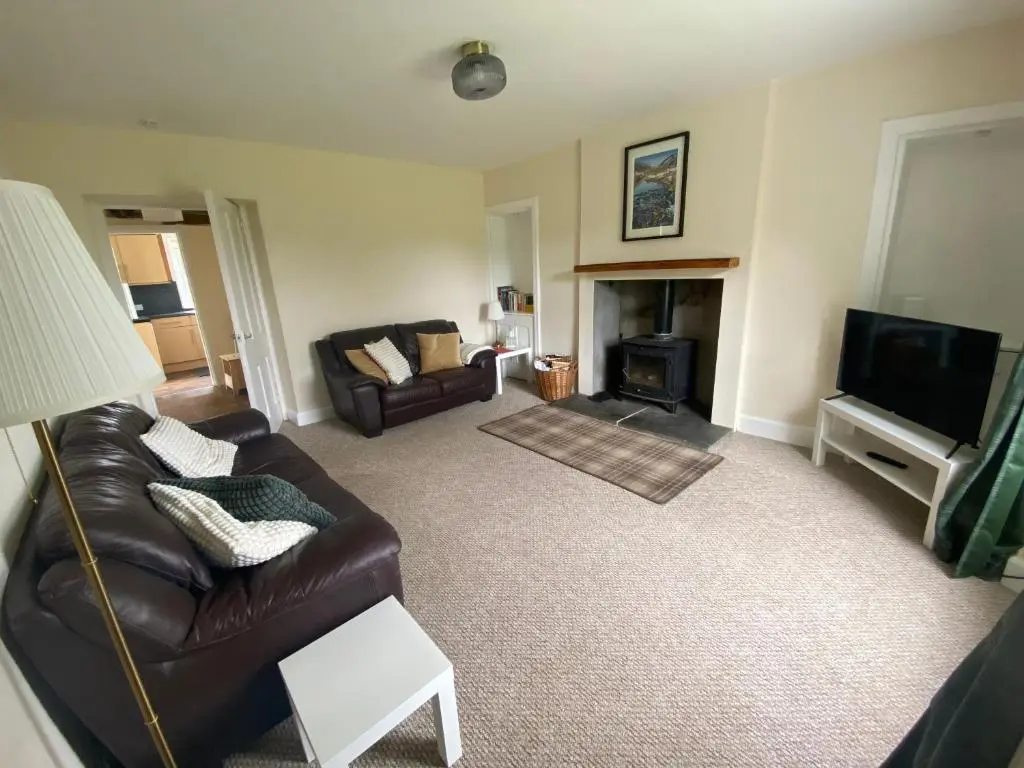 a living room with a leather couch and a television at Alltachbeg in Tomintoul
