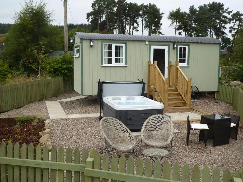 a small green house with a hot tub and chairs at Shepherds View in Glenshee