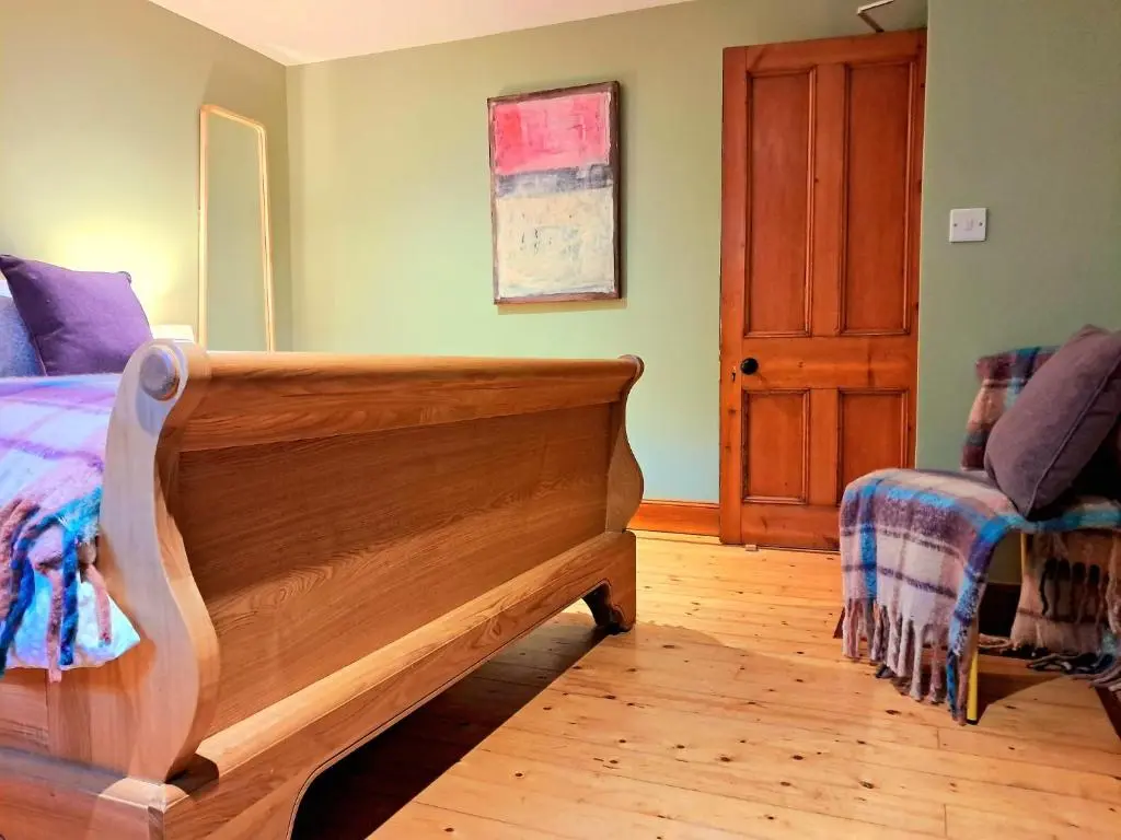a bedroom with a wooden bed and a chair at Apartment 42b by the river in Inverness