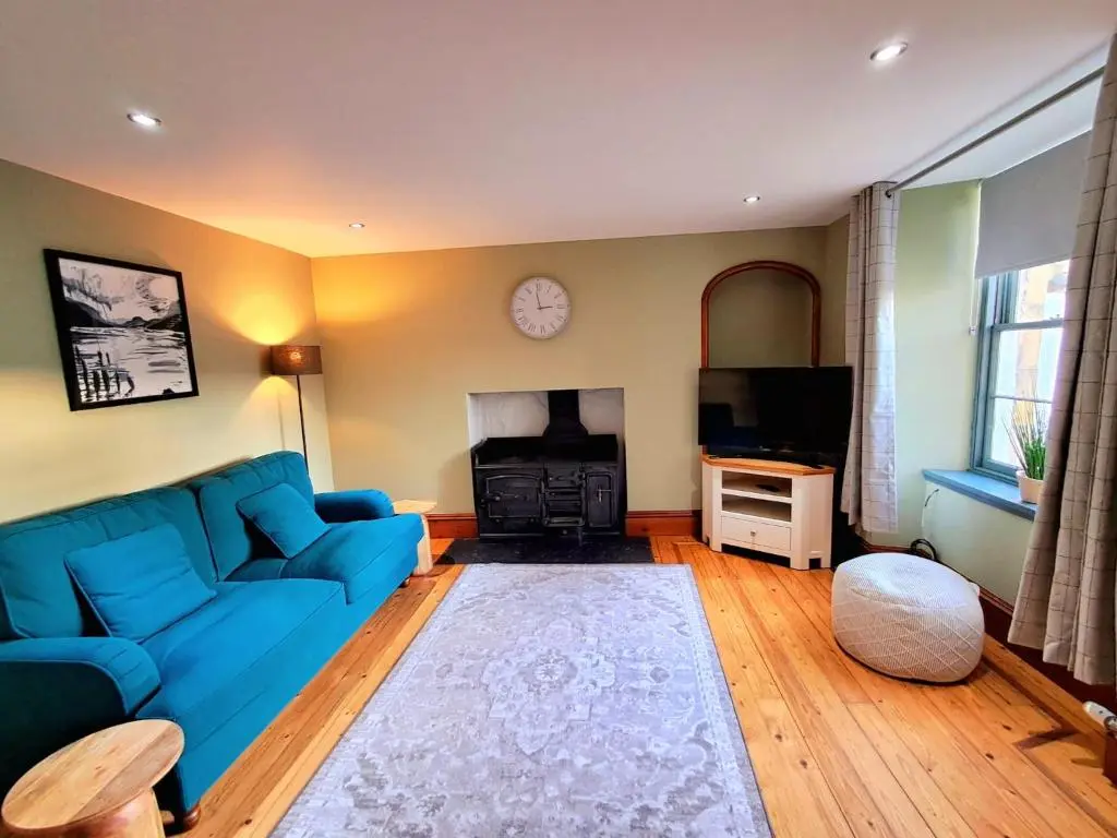 a living room with a blue couch and a fireplace at Apartment 42b by the river in Inverness