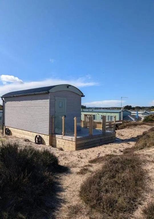 a small shack on a beach with the ocean in the background at Shephards Hut by the Beach in Findhorn