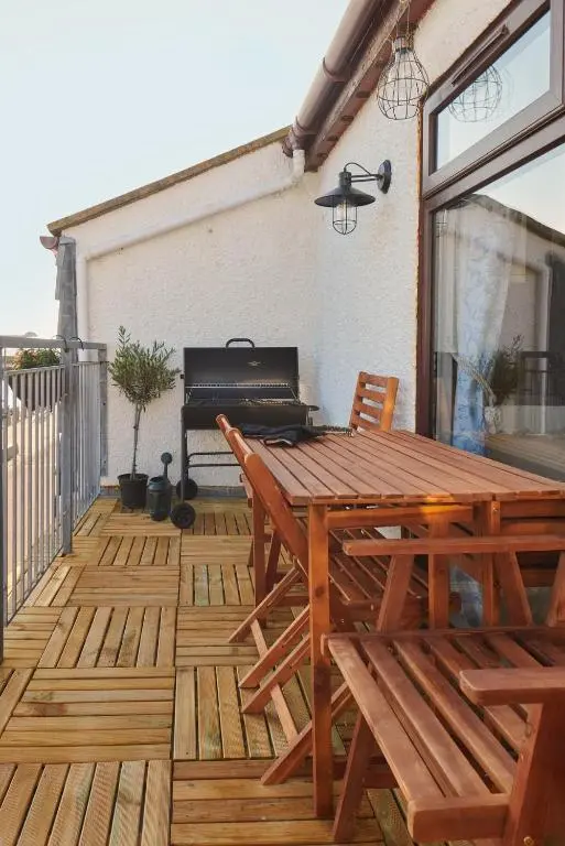 a wooden deck with a picnic table and a grill at The Sandpiper in Burghead