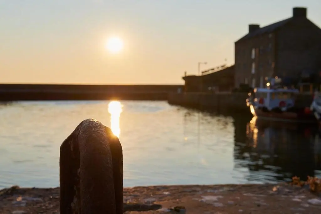 a sun setting over a body of water with boats at The Sandpiper in Burghead