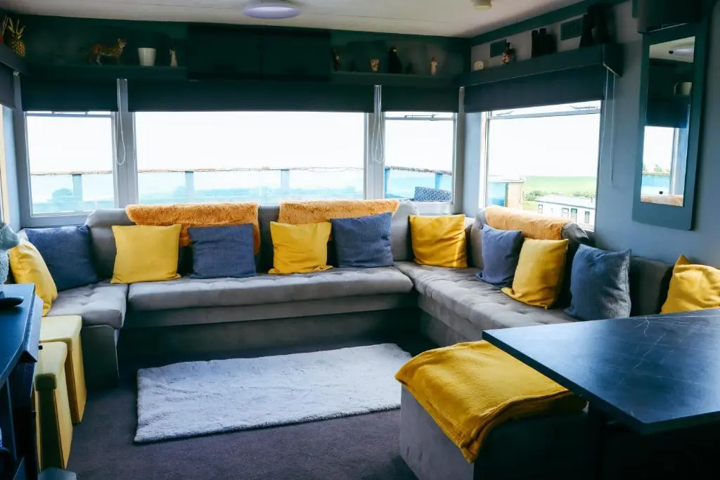 a living room with a couch with yellow and blue pillows at Caravan Nr 51 Only for Family Holiday