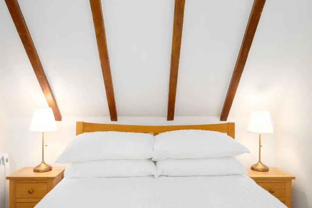 a bed with white pillows and two lamps on tables at Seabreeze Cottage, 17 Seatown, Gardenstown in Gardenstown