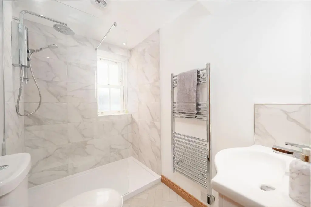 a white bathroom with a shower and a sink at Seabreeze Cottage, 17 Seatown, Gardenstown in Gardenstown