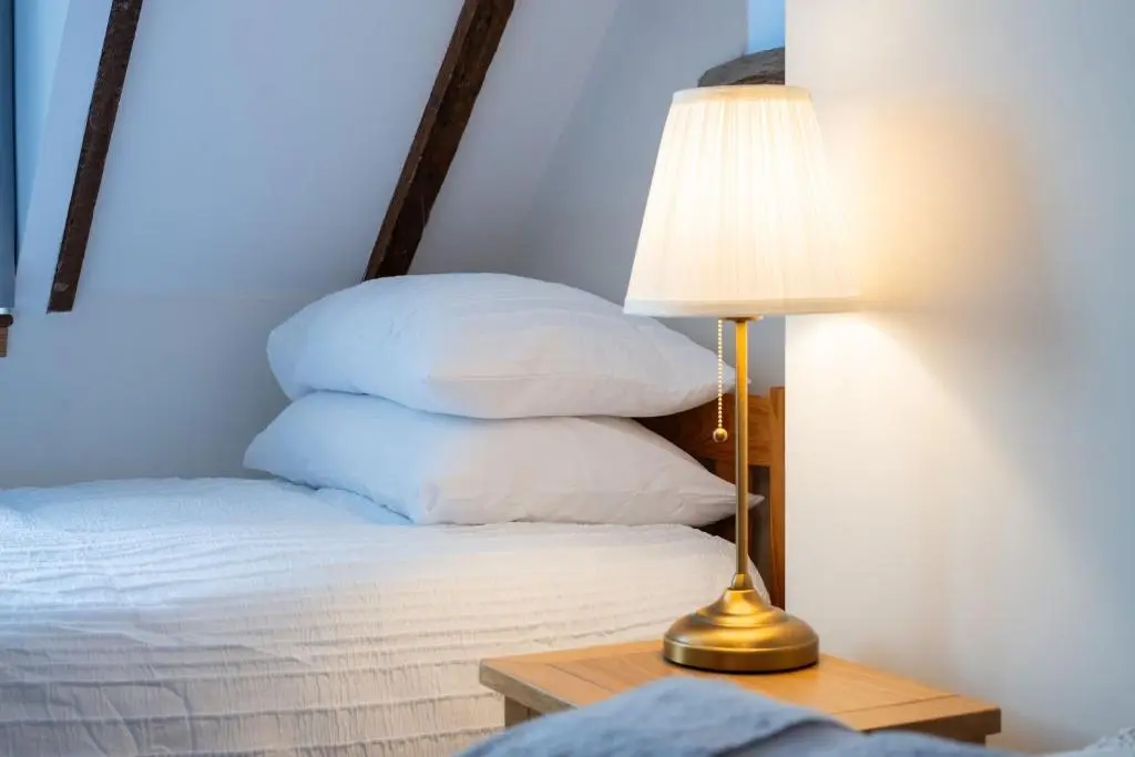 a lamp sitting next to a bed with white pillows at Seabreeze Cottage, 17 Seatown, Gardenstown in Gardenstown