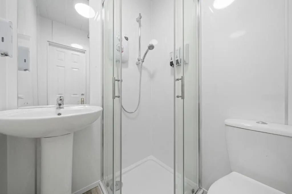 a white bathroom with a shower and a sink at mySTAYINN Cedar Villa 9 Bedroom House - Inverness in Inverness