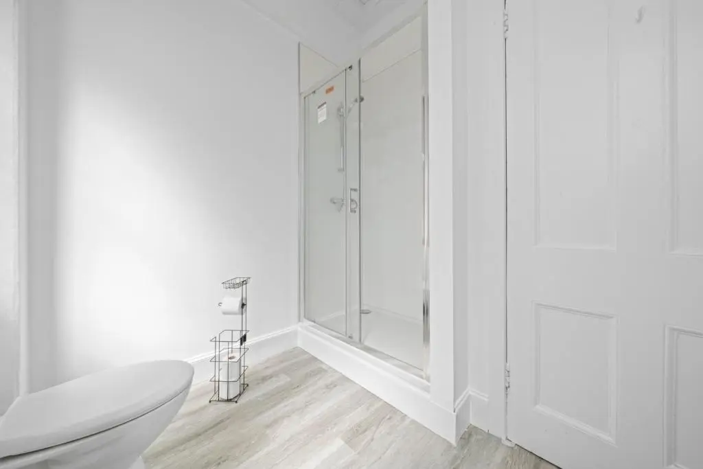 a white bathroom with a toilet and a glass shower at mySTAYINN Cedar Villa 9 Bedroom House - Inverness in Inverness