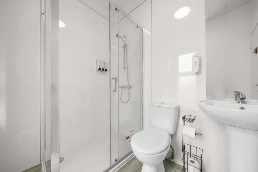 a white bathroom with a toilet and a sink at mySTAYINN Cedar Villa Guest House in Inverness