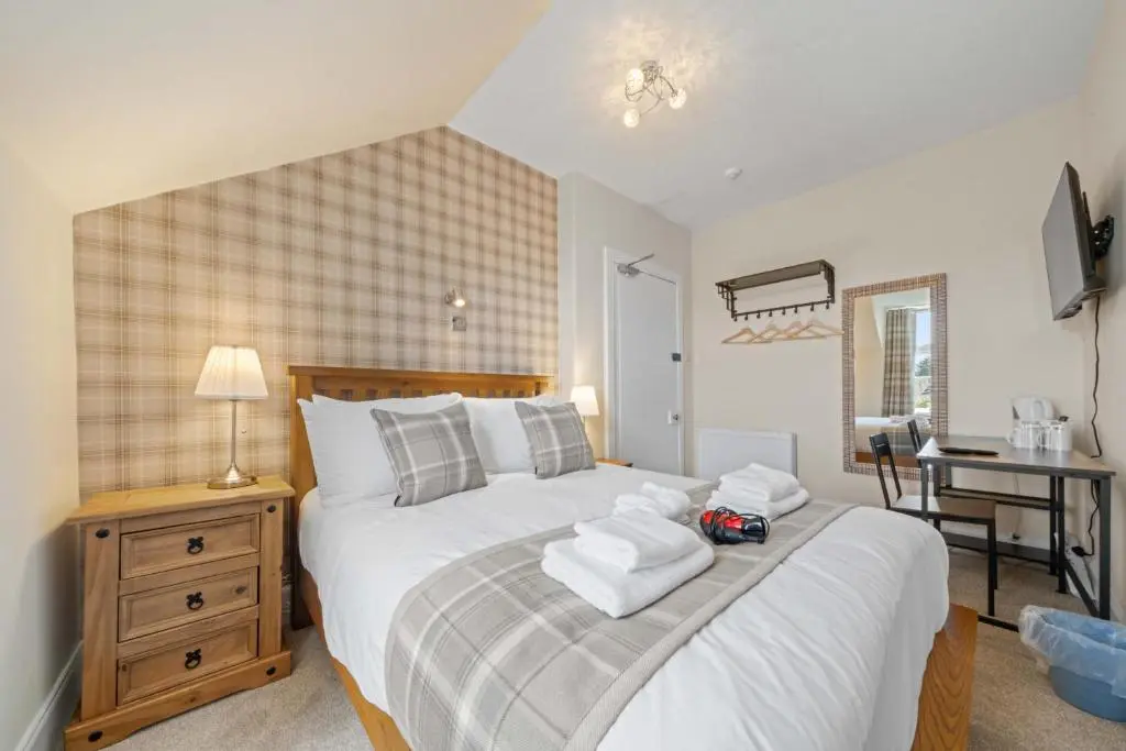 a bedroom with a large bed with towels on it at mySTAYINN Cedar Villa Guest House in Inverness