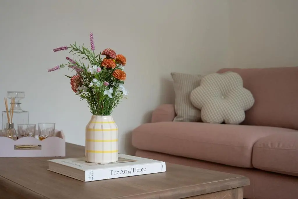 a vase with flowers on a table in a living room at Hideaway Cottage W Hot Tub in Portsoy