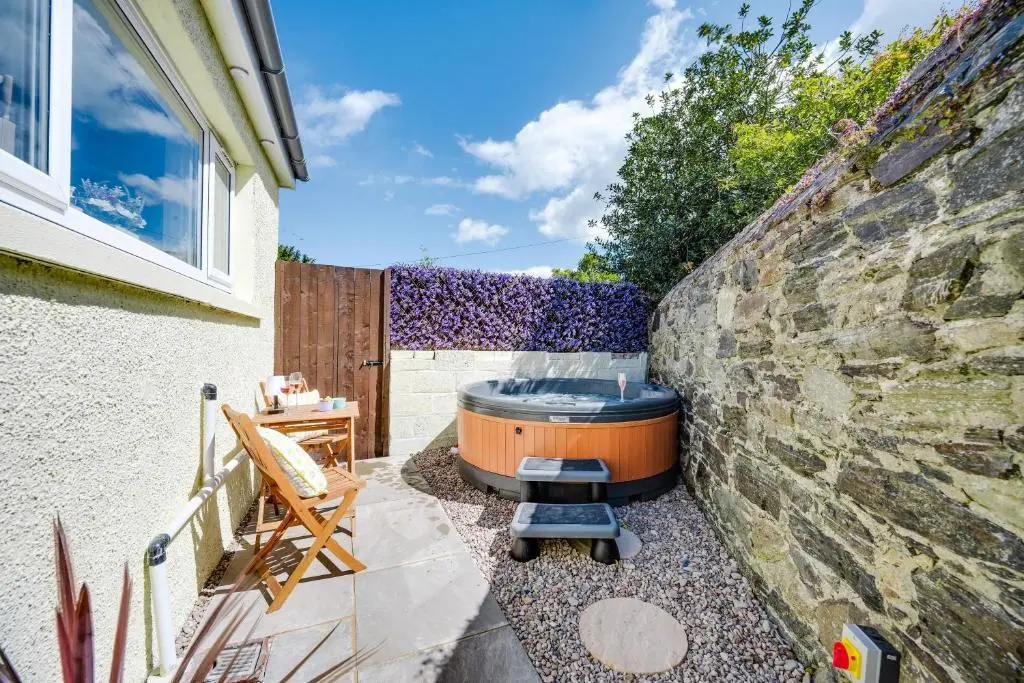 a hot tub in a yard next to a stone wall at Hideaway Cottage W Hot Tub in Portsoy