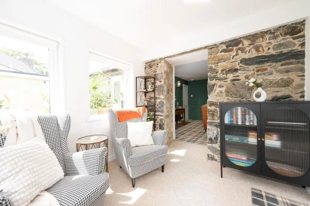 a living room with two chairs and a stone wall at The Garden Cottage with Hot Tub in Portsoy