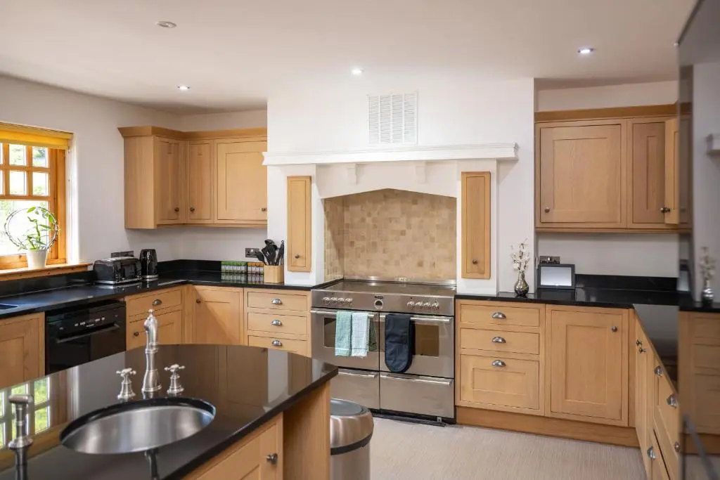 a large kitchen with wooden cabinets and a sink at Old Distillery Lodge in Kingussie