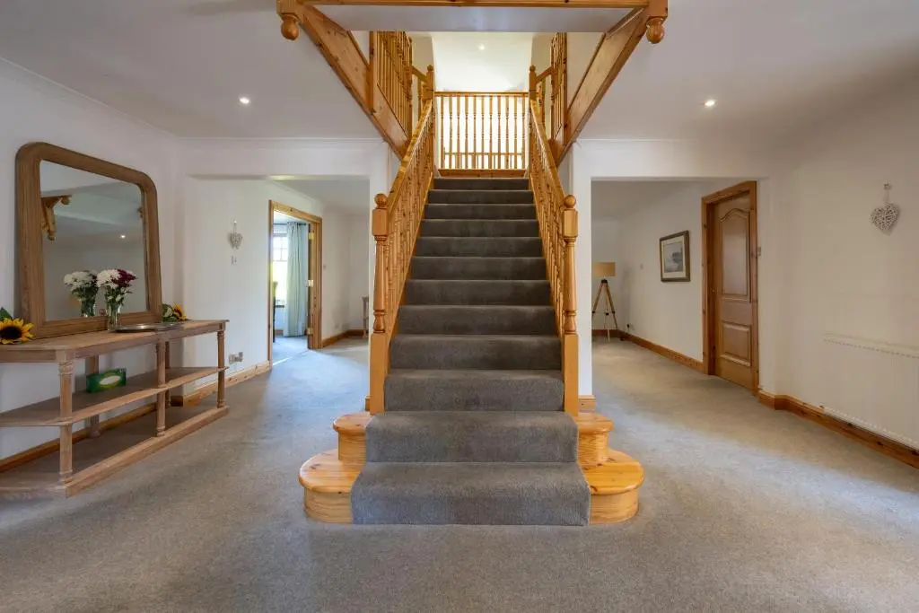 a winding staircase in a home with a wooden stair case at Old Distillery Lodge in Kingussie
