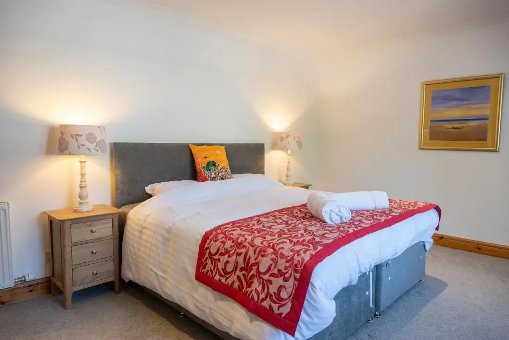 a bedroom with a large bed and a night stand at Old Distillery Lodge in Kingussie