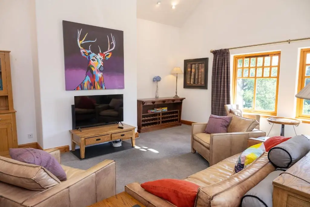 a living room with two couches and a tv at Old Distillery Lodge in Kingussie