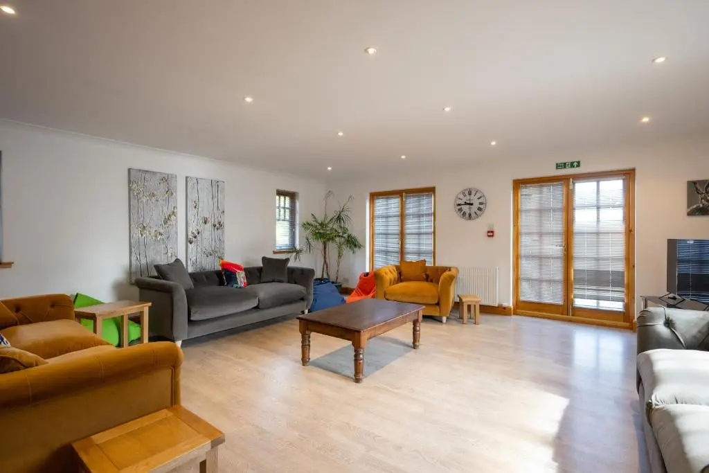 a living room with couches and a table at Old Distillery Lodge in Kingussie