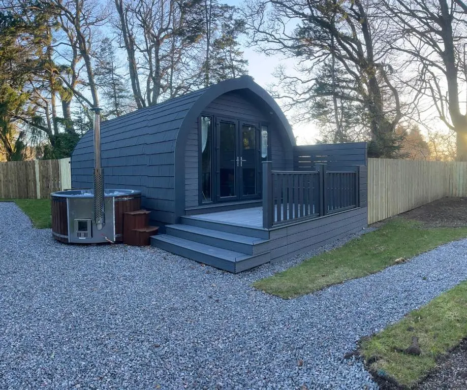 a small cabin with a porch and a fence at Rosevalley luxury Glamping grouse pods in Cawdor