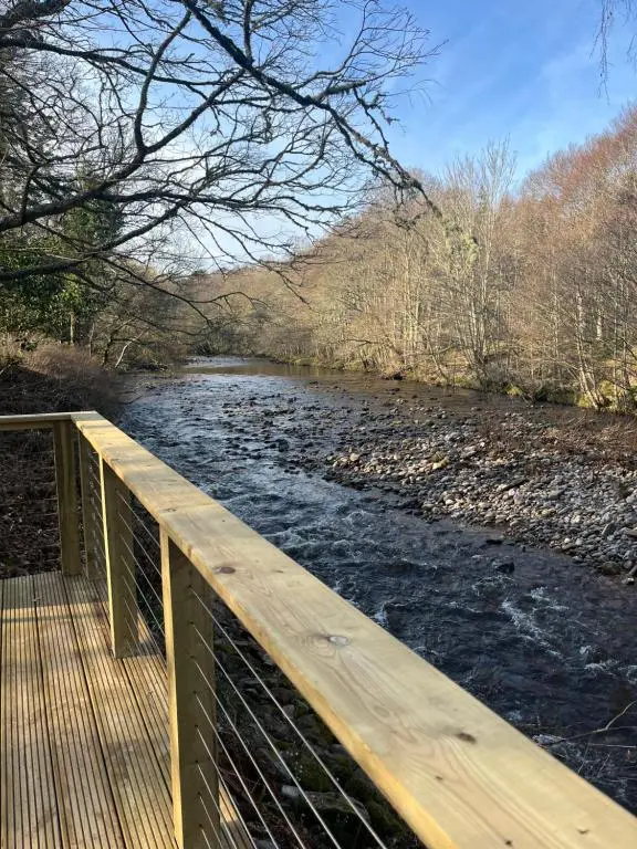 a wooden bridge over a river with water at Rosevalley luxury Glamping grouse pods in Cawdor