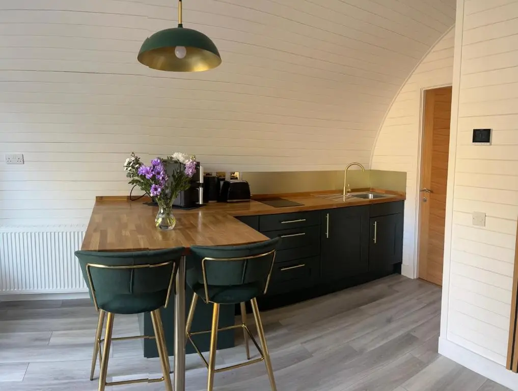 a kitchen with a table with a vase of flowers on it at Rosevalley luxury Glamping grouse pods in Cawdor
