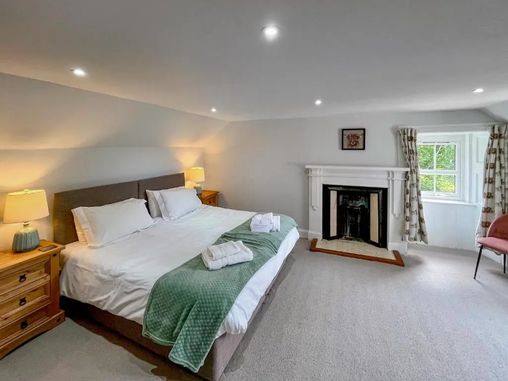 a bedroom with a large bed and a fireplace at Rottal Farmhouse in Millton of Clova