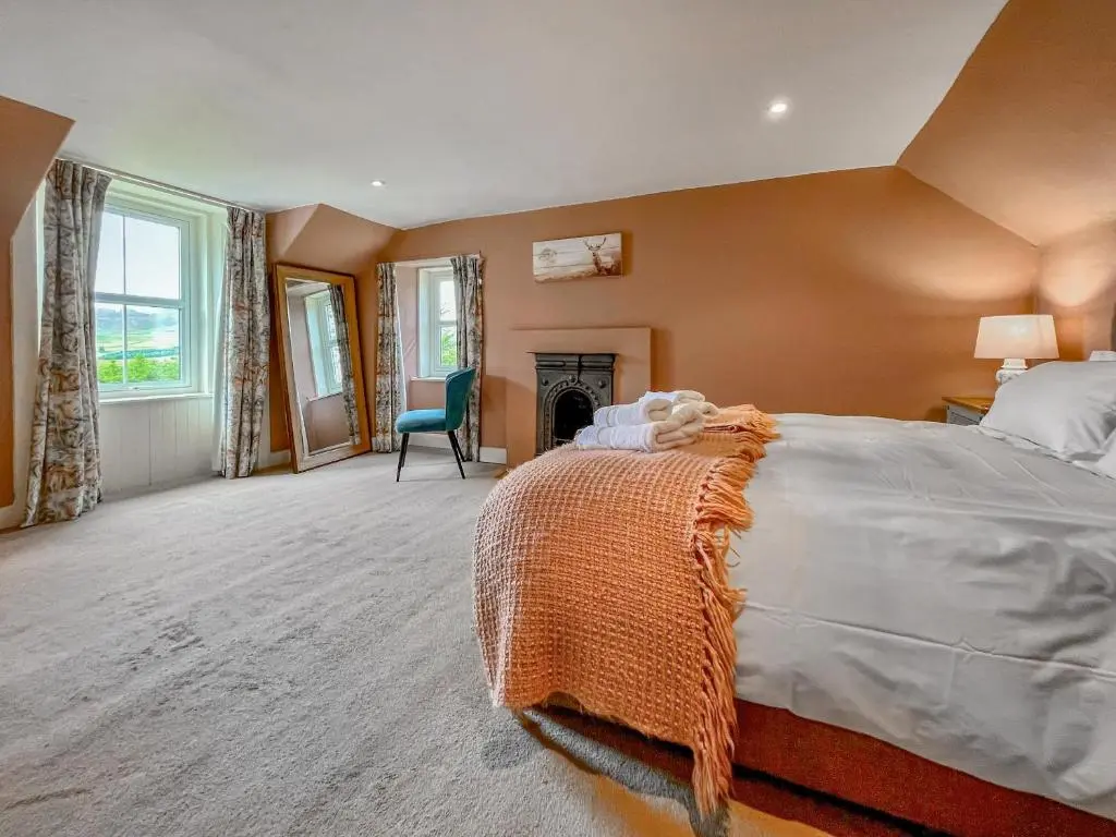 a large bedroom with a bed and a fireplace at Rottal Farmhouse in Millton of Clova