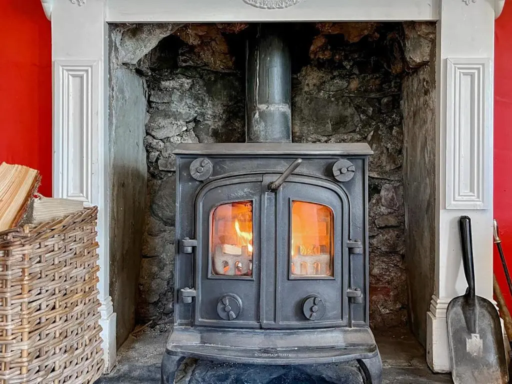 a stove in a room with a stone wall at Rottal Farmhouse in Millton of Clova