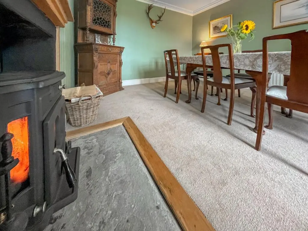 a living room with a fireplace and a dining table at Rottal Farmhouse in Millton of Clova