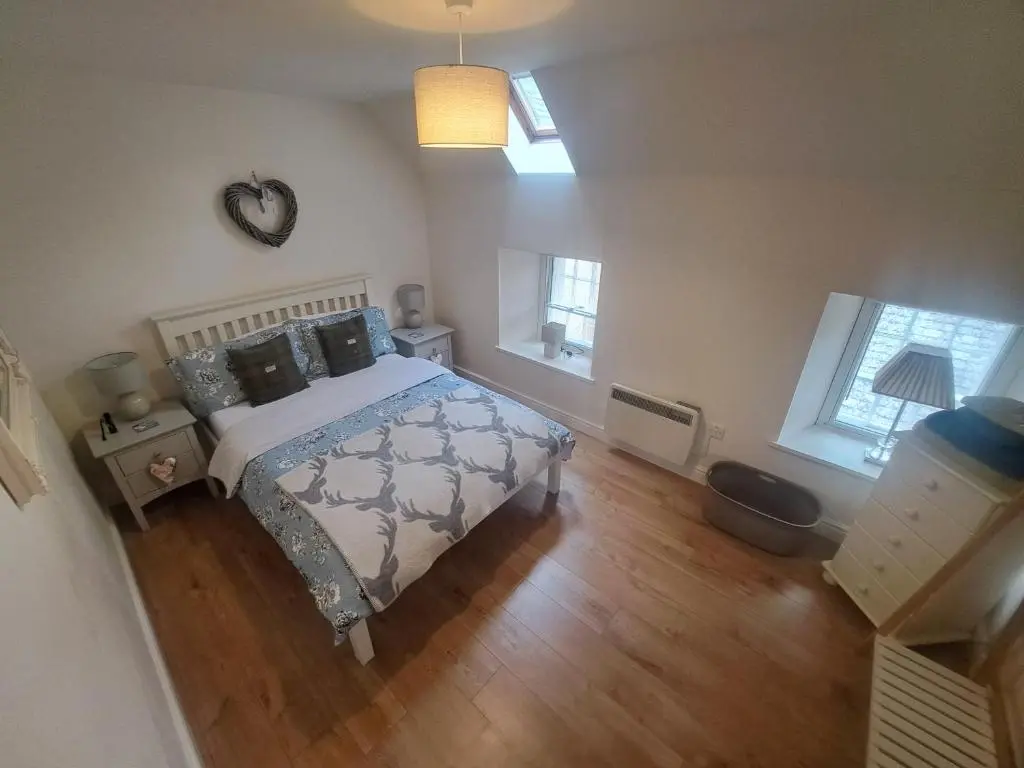 a bedroom with a bed and a wooden floor at Tweed Apartment, Golspie in Golspie