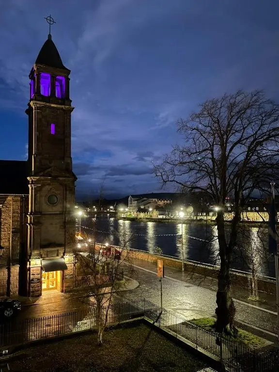 a clock tower with purple lights on it at night at River-View Loft, sleeps 4, with parking in Inverness