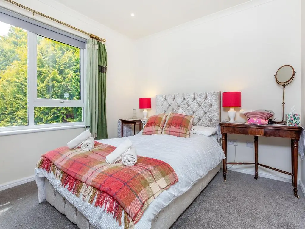 a bedroom with a bed and a desk and a window at Highland Sanctuary in Dornoch