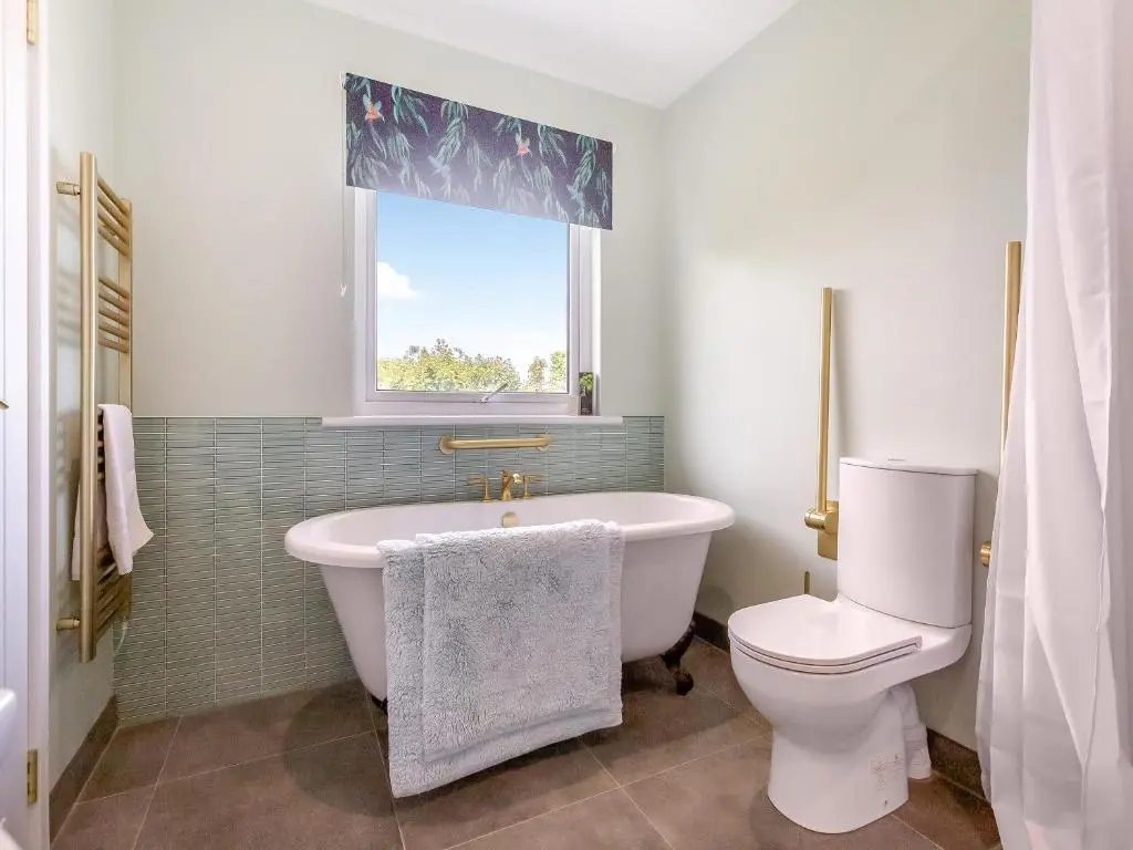 a bathroom with a tub and a toilet and a window at Highland Sanctuary in Dornoch