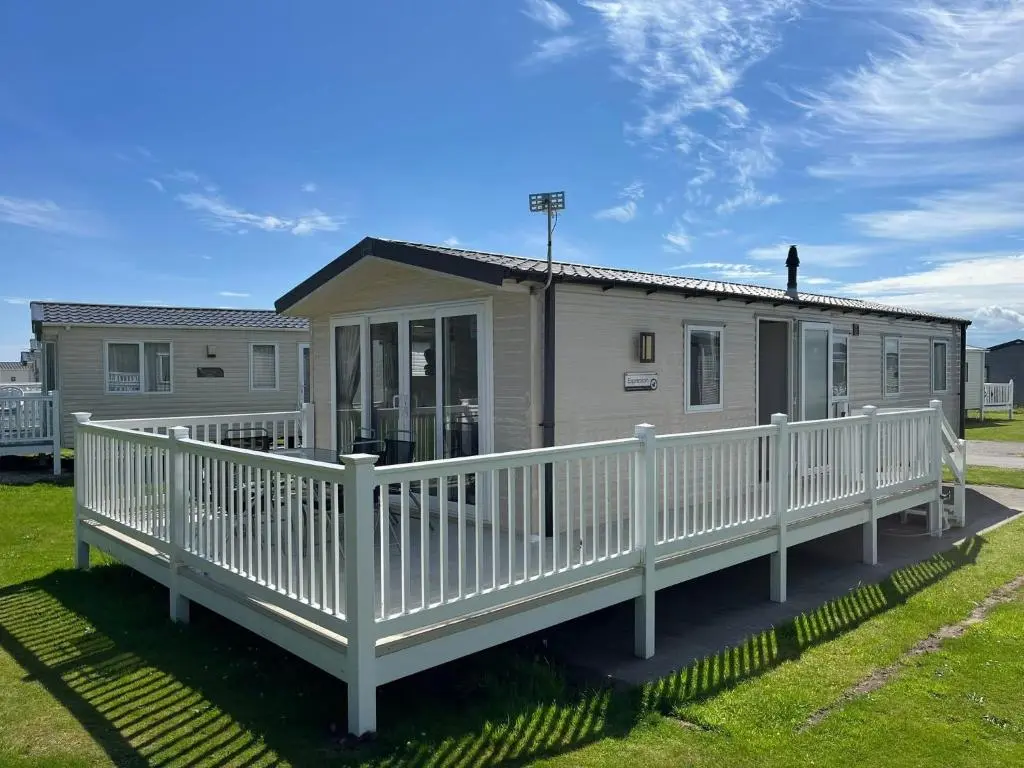 a mobile home with a porch and white railing at Sandy Shores in Embo
