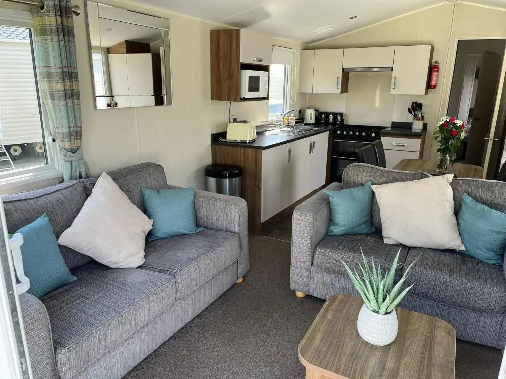 a living room with two couches and a kitchen at Sandy Shores in Embo
