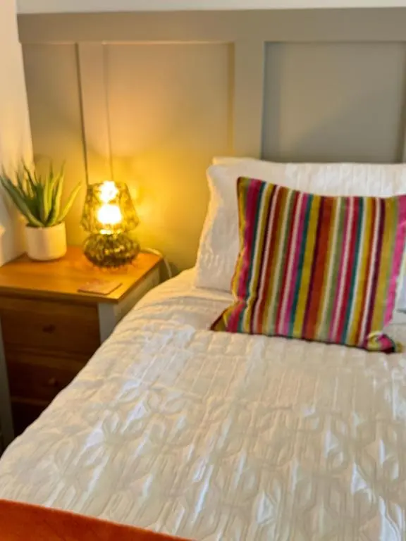 a bed with a pillow and a lamp on a night stand at Wellhouse Country Lodges and Hot Tubs in Tore