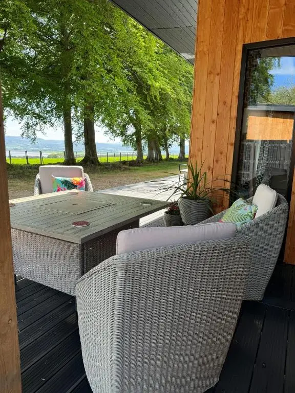 a patio with wicker chairs and a table on a porch at Wellhouse Country Lodges and Hot Tubs in Tore
